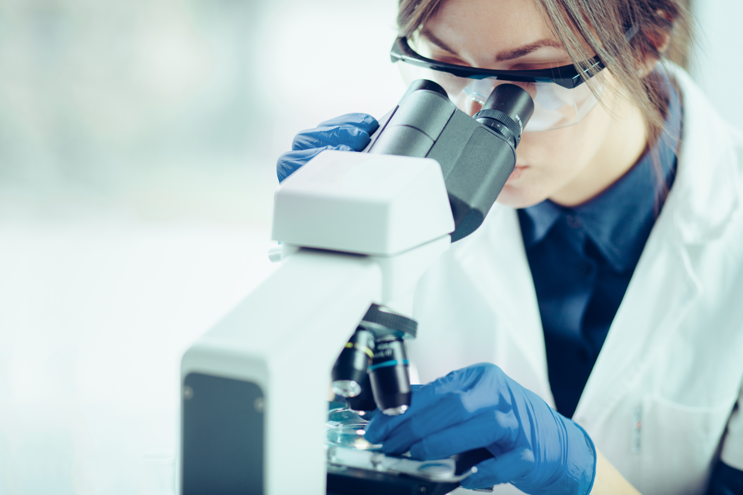 Laboratory assistant using a microscope